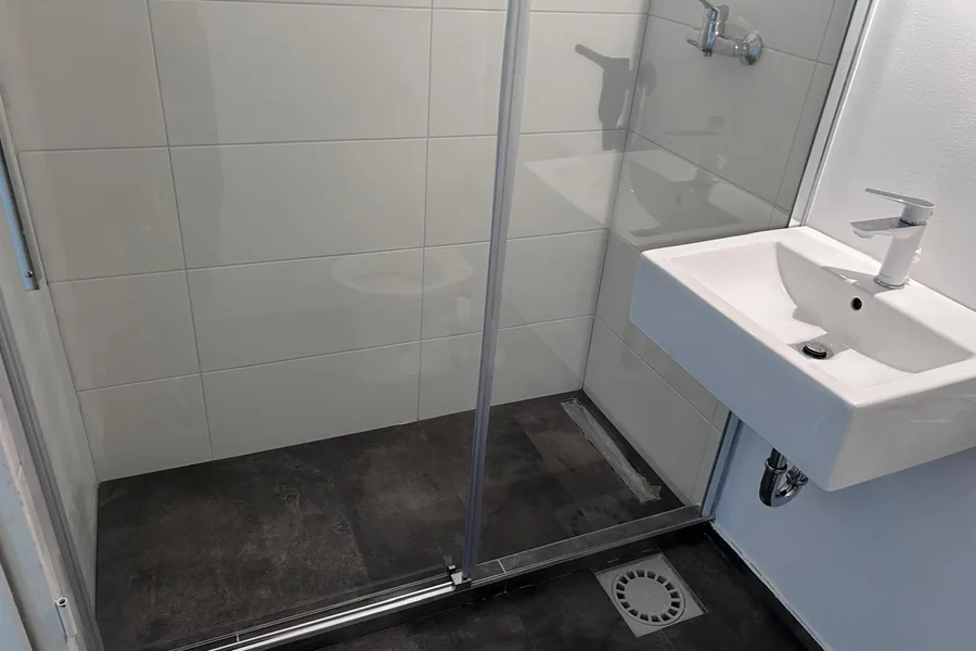 Badsanierung Berlin fertig — Dusche mit Glasabtrennung und Waschbecken